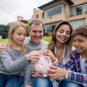 Portrait of a happy family outdoors saving money in a piggybank - home finances concepts